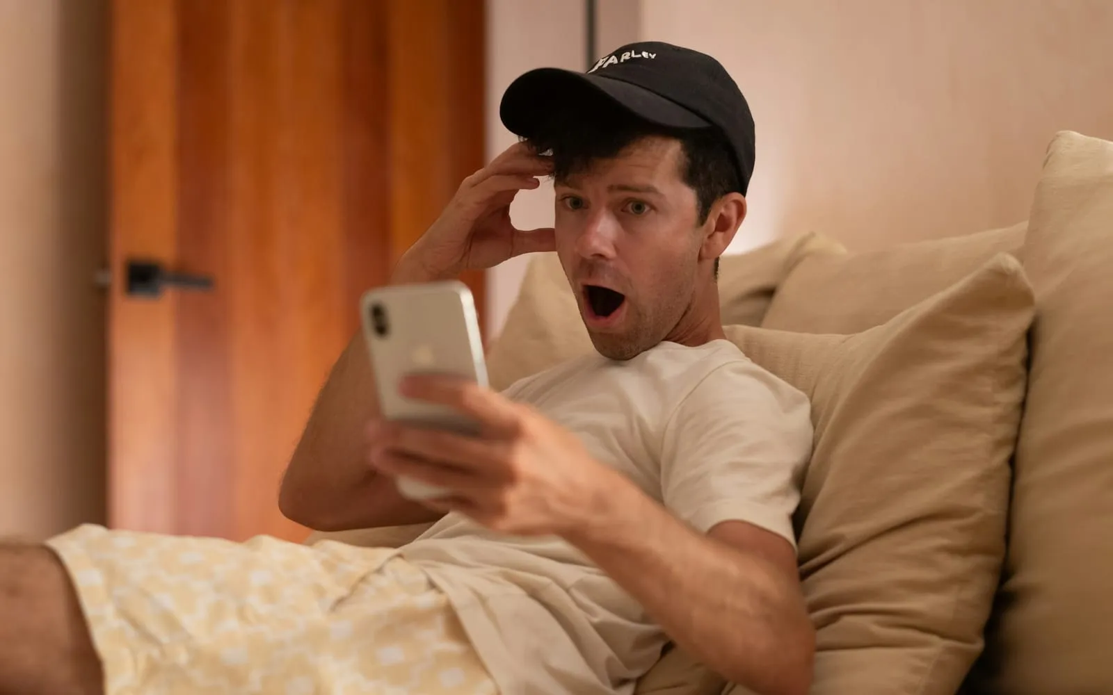 Homem surpreso olhando o celular no sofá